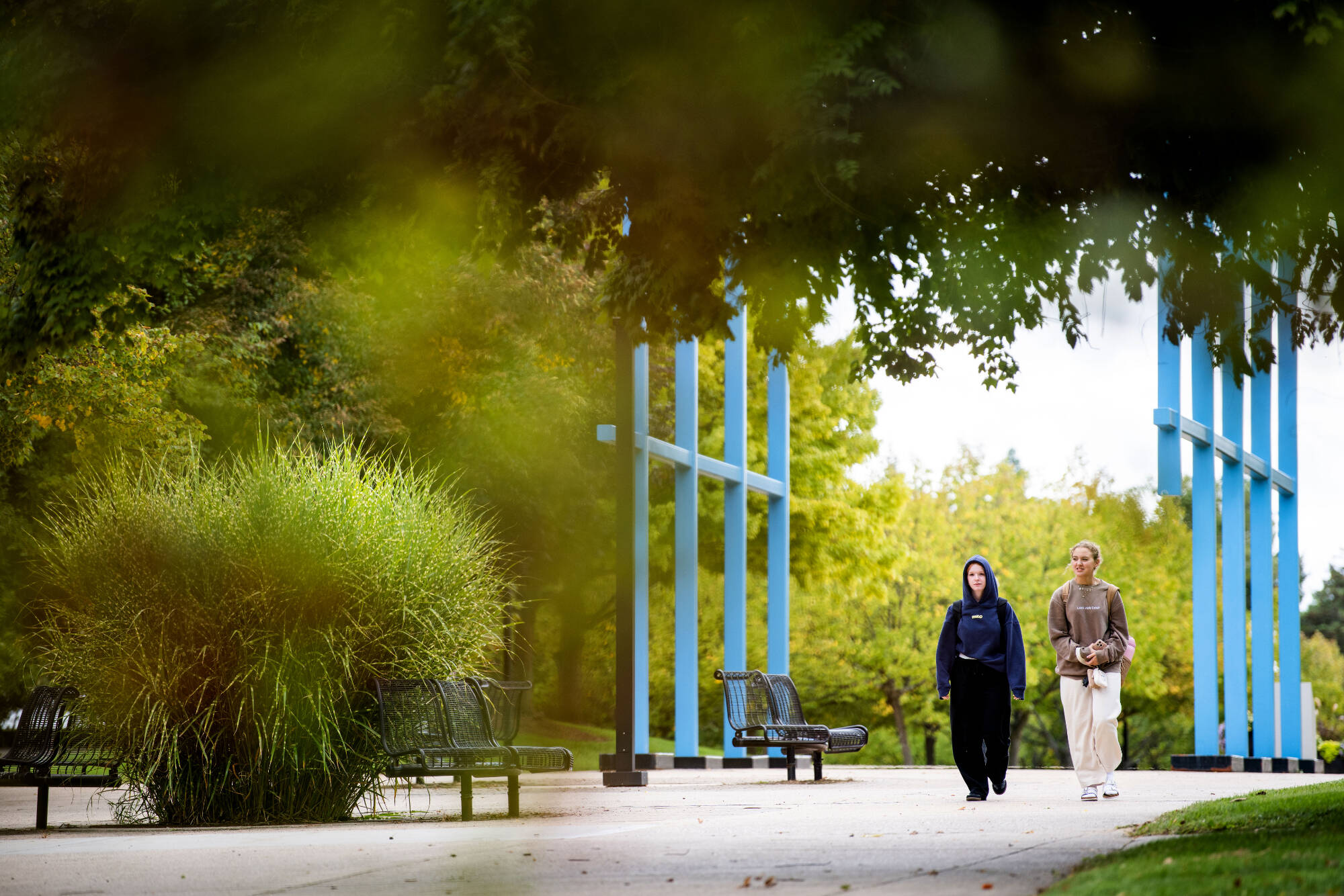 students walking under blue archway sculpture in allendale